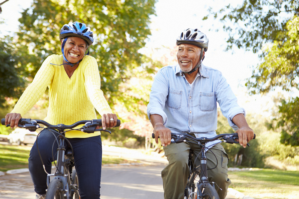 Senior couple riding through a park with their bikes