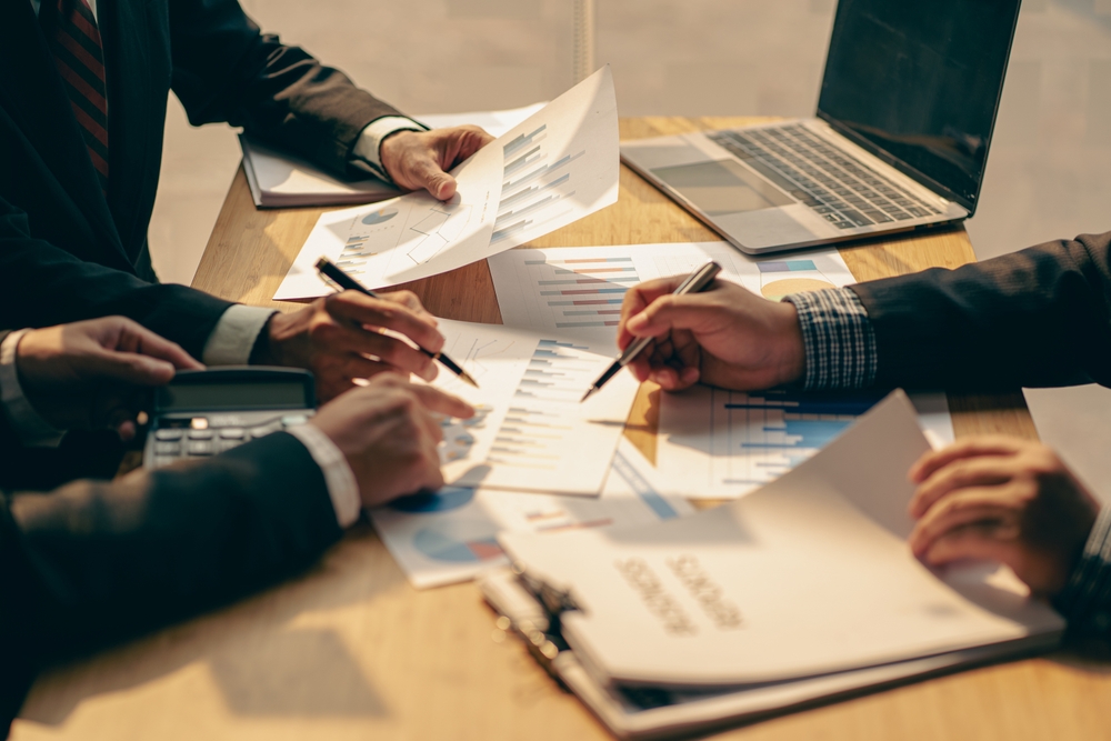 people sitting around a desk looking at paperwork together