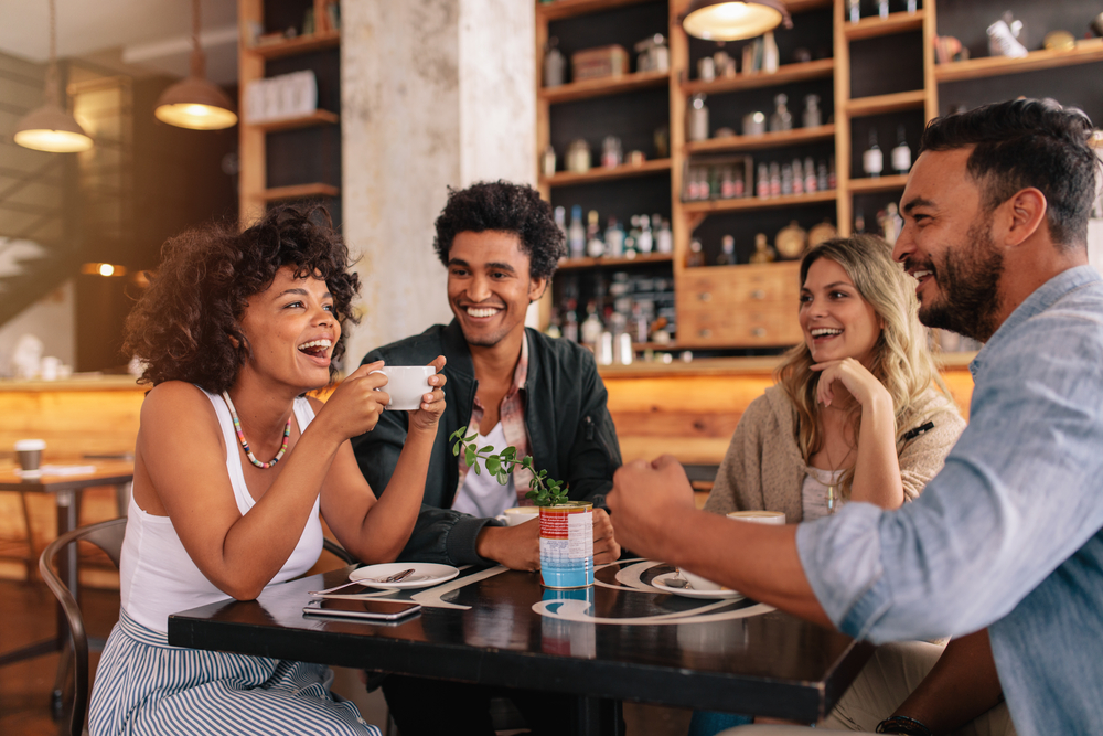 Group of friends laughing while seated at a restaurant table