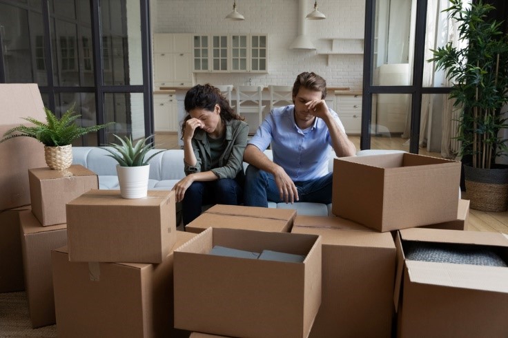 stressed out couple from moving, surrounded by lots of boxes