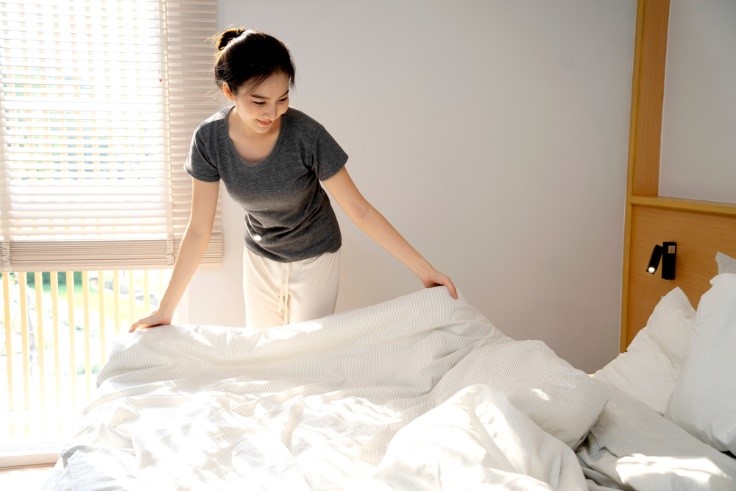 young asian woman making white bed