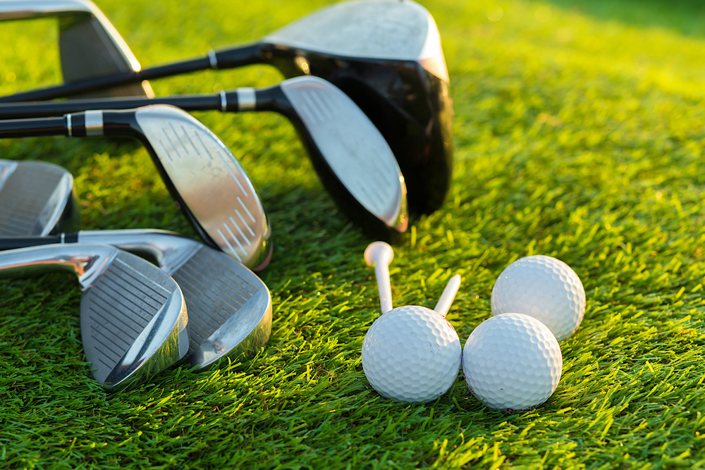 Golf ball and clubs on grass