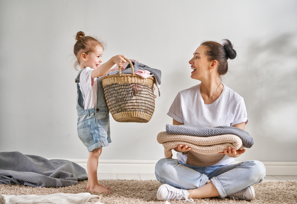 Beautiful-young-woman-and-child-girl-little-helper-are-having-fun-and-smiling-while-doing-laundry-at-home.